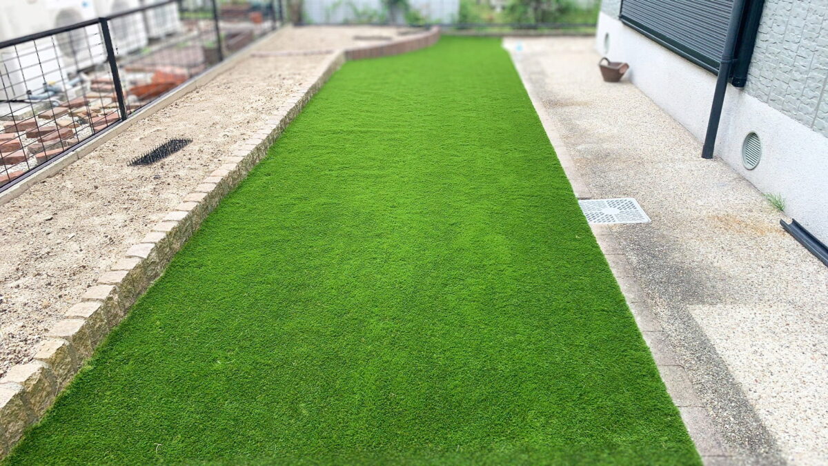 緑の人工芝が敷かれた庭。縁石で区切られ、周囲は砂利敷きで仕上げられている。