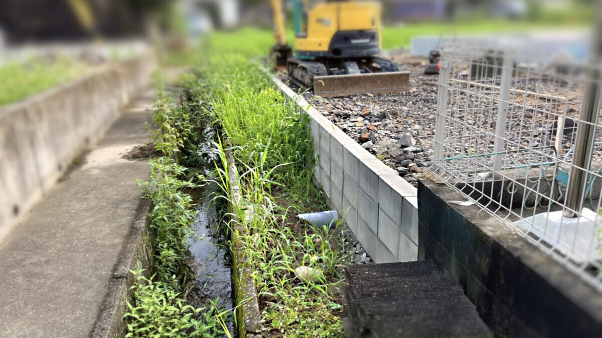雑草が繁茂した土の水路とコンクリート側溝の施工前状態