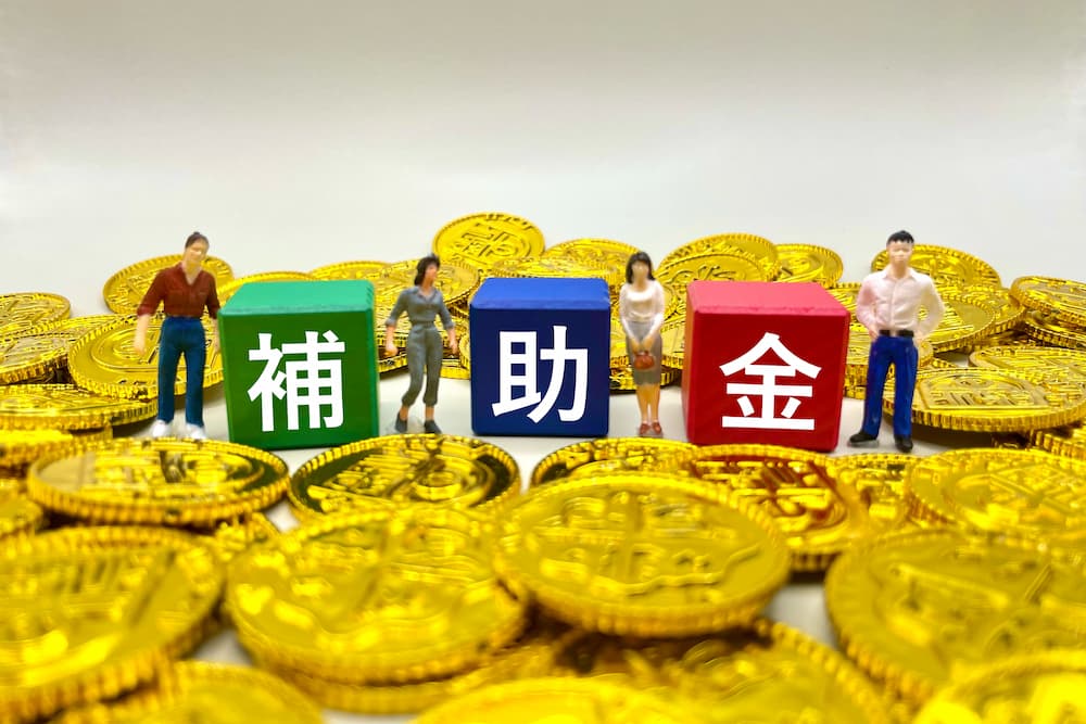 外構工事で活用できる補助金制度のイメージ｜補助金を表す色分けされたブロックとコイン、ミニチュア人形で表現