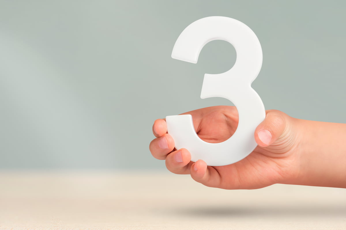 手に持った白い数字の3、補助金申請成功のための3つの重要ポイントを表すイメージ