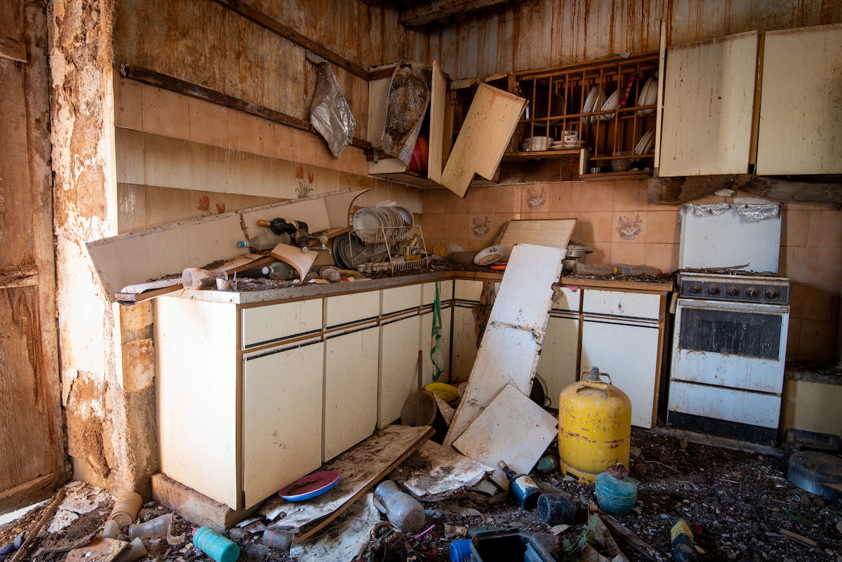 老朽化した空き家のキッチン。壁や設備が傷み、残置物が散乱している状態