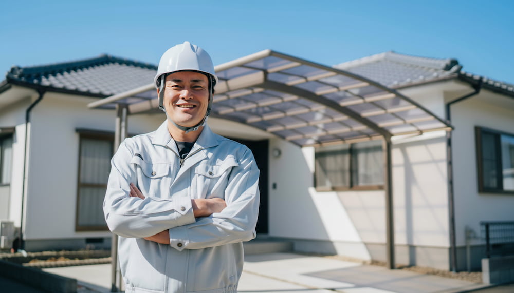 カーポートのある住宅前で腕を組む外構工事の専門業者