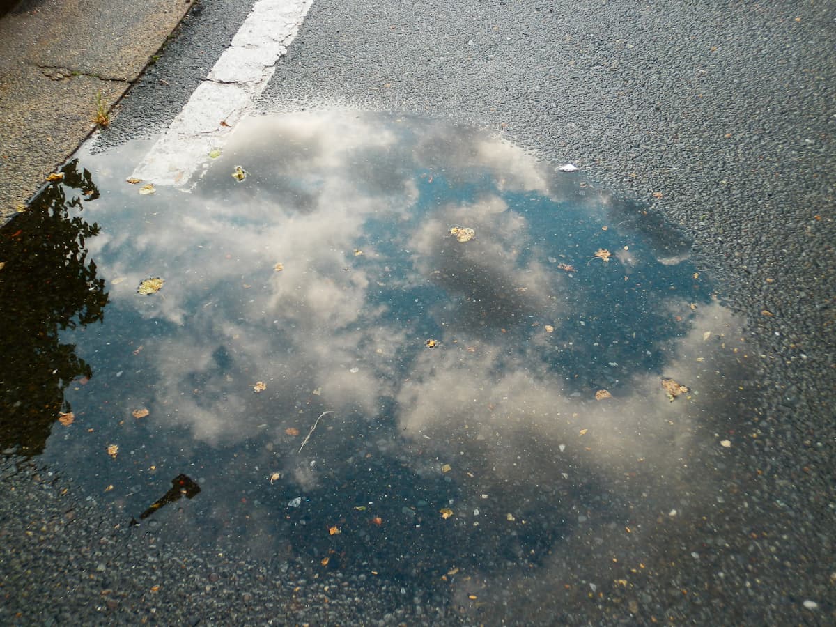 アスファルト舗装の駐車場にできた大きな水たまり。勾配不足による排水不良の例