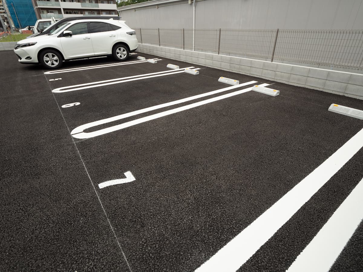 アスファルト舗装で整備された月極駐車場。区画線とフェンスが整った賃貸向けの仕上がり