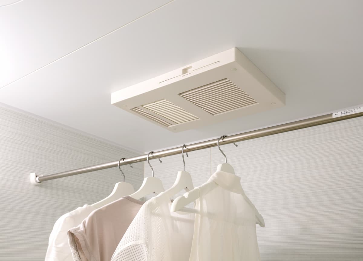 浴室の天井に取り付けられた暖房乾燥機。ポールに洗濯物が干してある